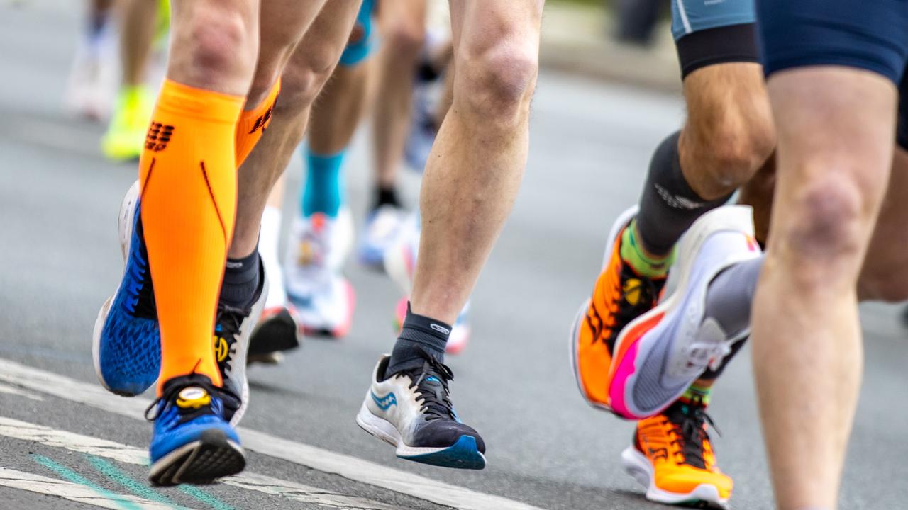 Nahaufnahme von Laufschuhen, Waden und Beinen der Läufer auf einer Strasse.