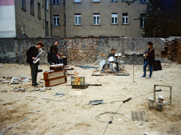 Privat organisiertes Punkkonzert in einem Ostberliner Hinterhof im Mai 1985. Vier Musiker spielen und singen in einem leeren Hinterhof vor einer bröckelnden Mauer. 