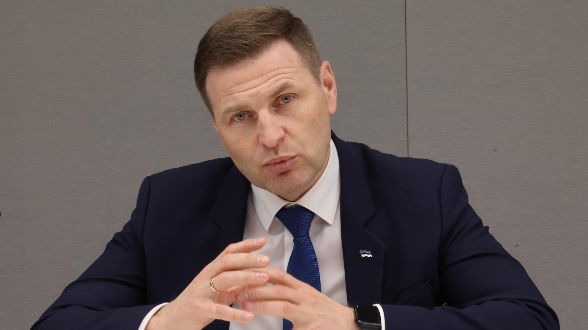 Pevkur im schwarzen Jackett sitzt vor einer hellen Wand und spricht. Pevkur im schwarzen Jackett sitzt vor einer hellen Wand und spricht.