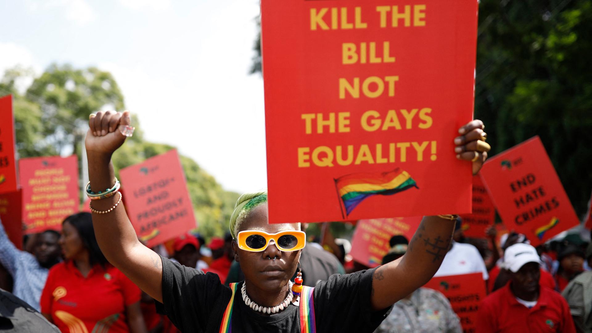 Der Queer Aktivist Papa De aus Uganda hält bei einer Demonstration im südafrikanischen Pretoria ein Plakat mit der Aufschrift: "Uganda, Kill the Bill, Not the Gays. Equality!"