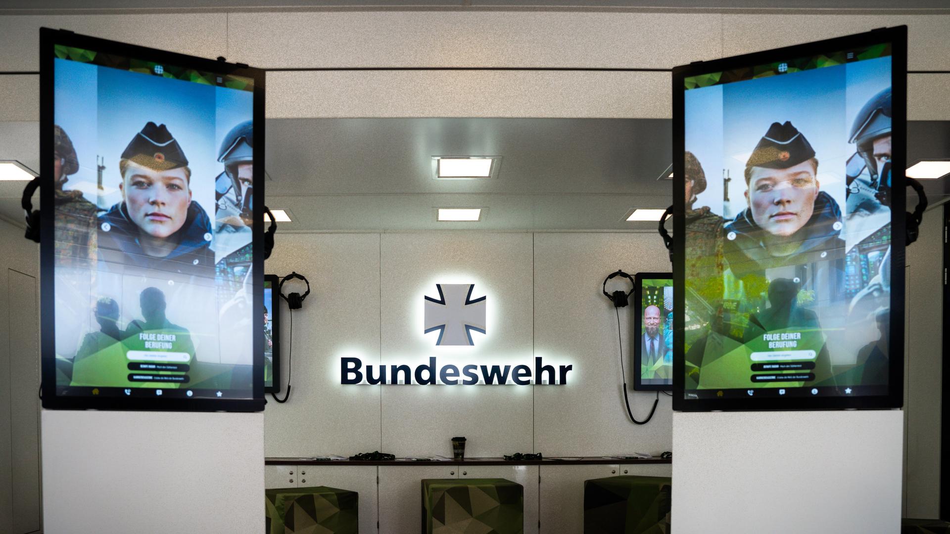  Logo der Bundeswehr im Karrieretruck der Bundeswehr inmitten von zwei Bildschirmen, die das Gesicht eines Soldaten in Uniform zeigen. 