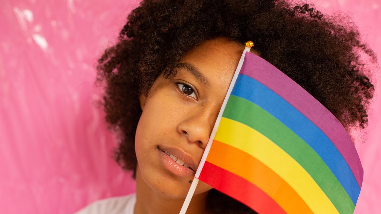 Eine Frau hält sich eine LGBTQI+ Flagge vor das Gesicht