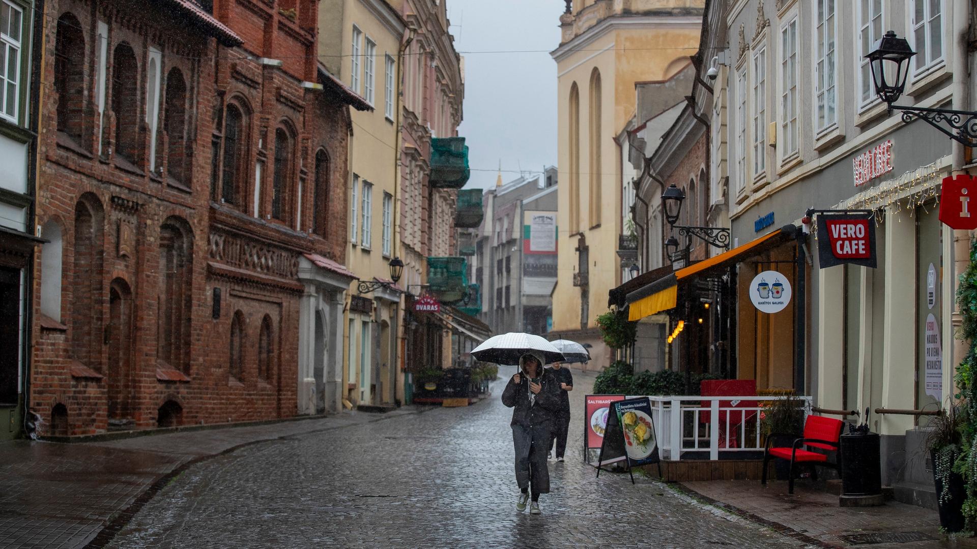 Litauen, Vilnius: Menschen suchen an einem regnerischen Tag unter Regenschirmen Schutz vor dem Regen. Litauen, Vilnius: Menschen suchen an einem regnerischen Tag unter Regenschirmen Schutz vor dem Regen.