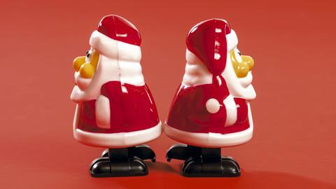 Zwei kleine Weihnachtsmannfiguren stehen mit dem Rücken zueinander. Zwei kleine Weihnachtsmannfiguren stehen mit dem Rücken zueinander.