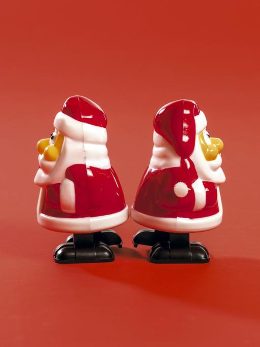 Zwei kleine Weihnachtsmannfiguren stehen mit dem Rücken zueinander.