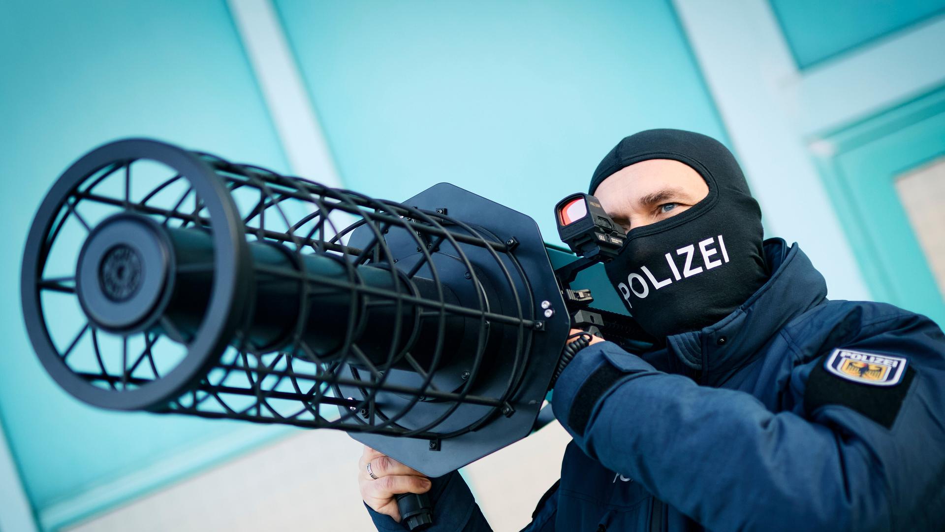 Ein Bundespolizist hält einen schwarze Jammer, eine Waffe zur Drohnenabwehr, auf seiner Schulter. Ein Bundespolizist hält einen schwarze Jammer, eine Waffe zur Drohnenabwehr, auf seiner Schulter.