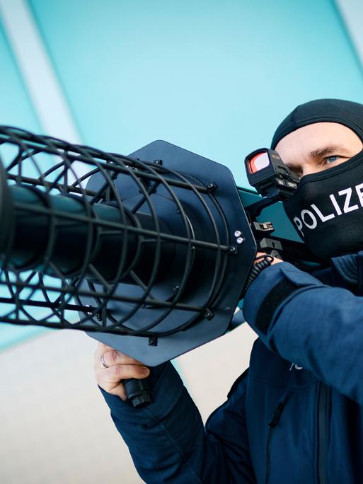 Ein Bundespolizist hält einen schwarze Jammer, eine Waffe zur Drohnenabwehr, auf seiner Schulter. Ein Bundespolizist hält einen schwarze Jammer, eine Waffe zur Drohnenabwehr, auf seiner Schulter.