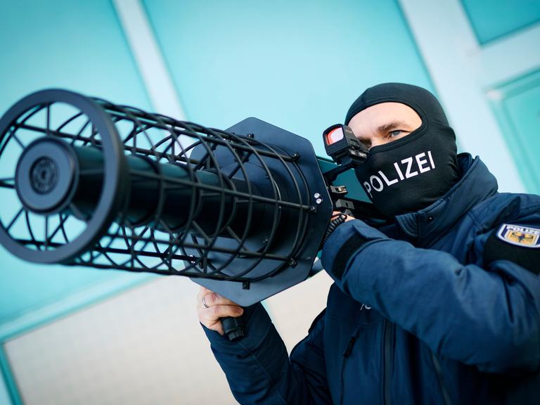 Ein Bundespolizist hält einen schwarze Jammer, eine Waffe zur Drohnenabwehr, auf seiner Schulter. Ein Bundespolizist hält einen schwarze Jammer, eine Waffe zur Drohnenabwehr, auf seiner Schulter.