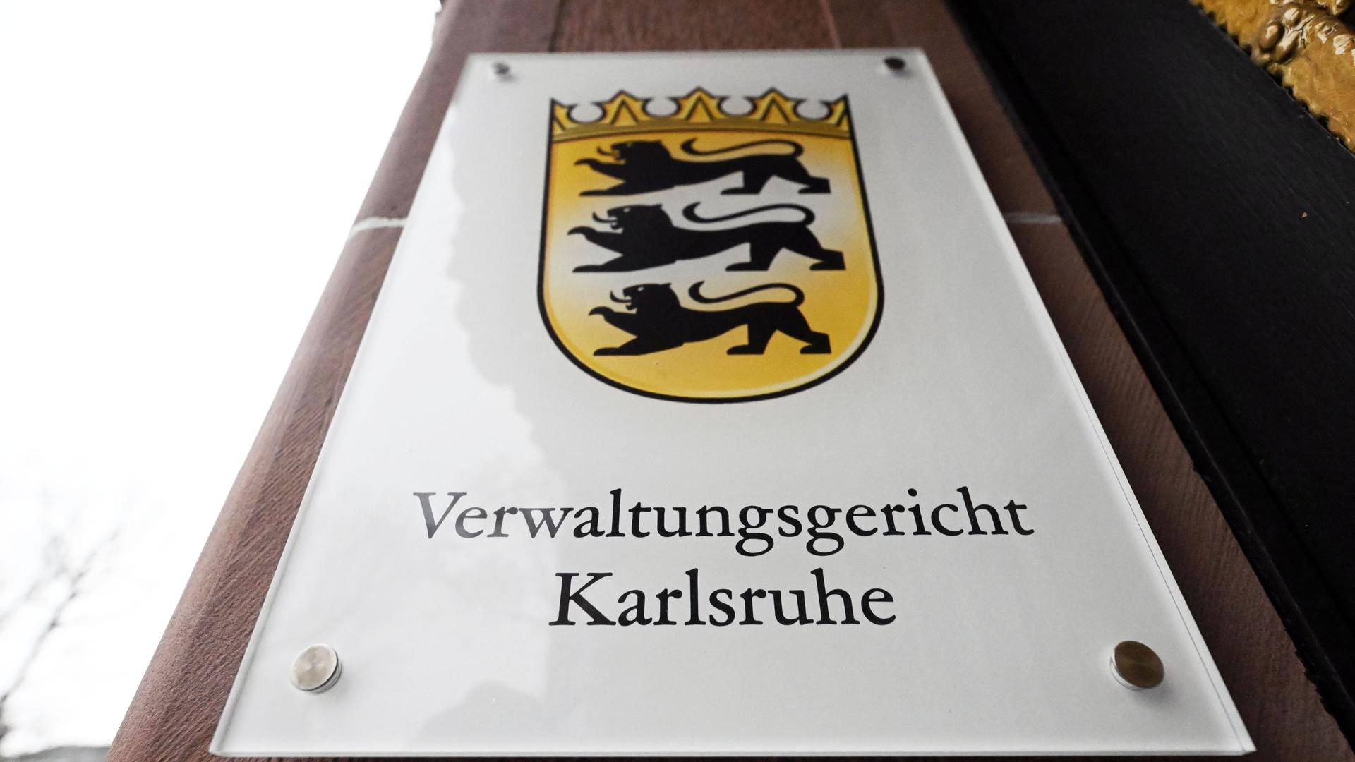 Ein Hinweisschild mit dem Landeswappen von Baden-Württemberg und dem Schriftzug „Verwaltungsgericht Karlsruhe“ am Eingang des Gerichtsgebäudes.
Ein Hinweisschild mit dem Landeswappen von Baden-Württemberg und dem Schriftzug „Verwaltungsgericht Karlsruhe“ am Eingang des Gerichtsgebäudes.