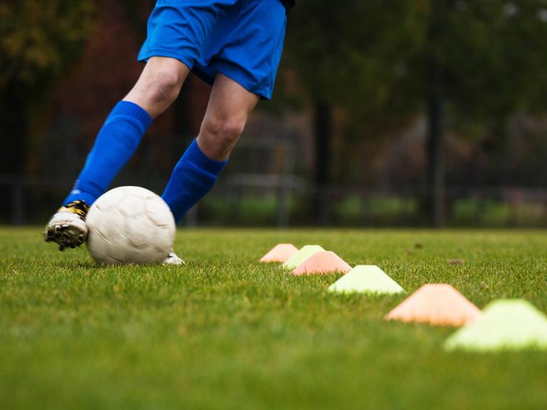 Ein Fußballspieler dribbelt im Training zwischen Hütchen hindurch (Symbolbild)