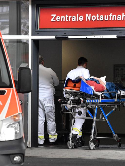 Ein Patient wird in die Zentrale Notaufnahme der Uniklinik Düsseldorf gebracht. Links im Bild steht ein Rettungswagen.