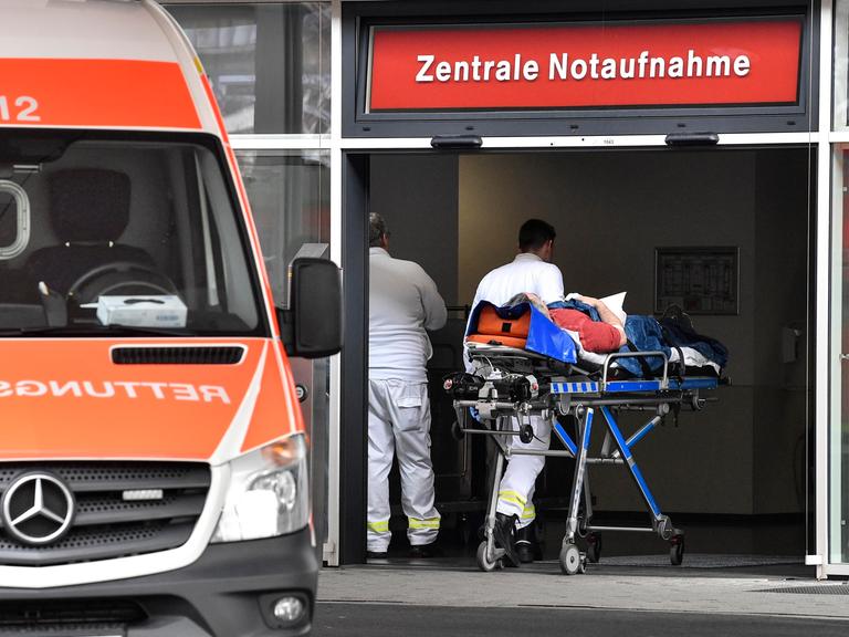 Ein Patient wird in die Zentrale Notaufnahme der Uniklinik Düsseldorf gebracht. Links im Bild steht ein Rettungswagen.