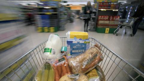 Das Symbolbild zeigt einen Einkaufswagen in einem Supermarkt, der mit Artikeln befüllt wird.