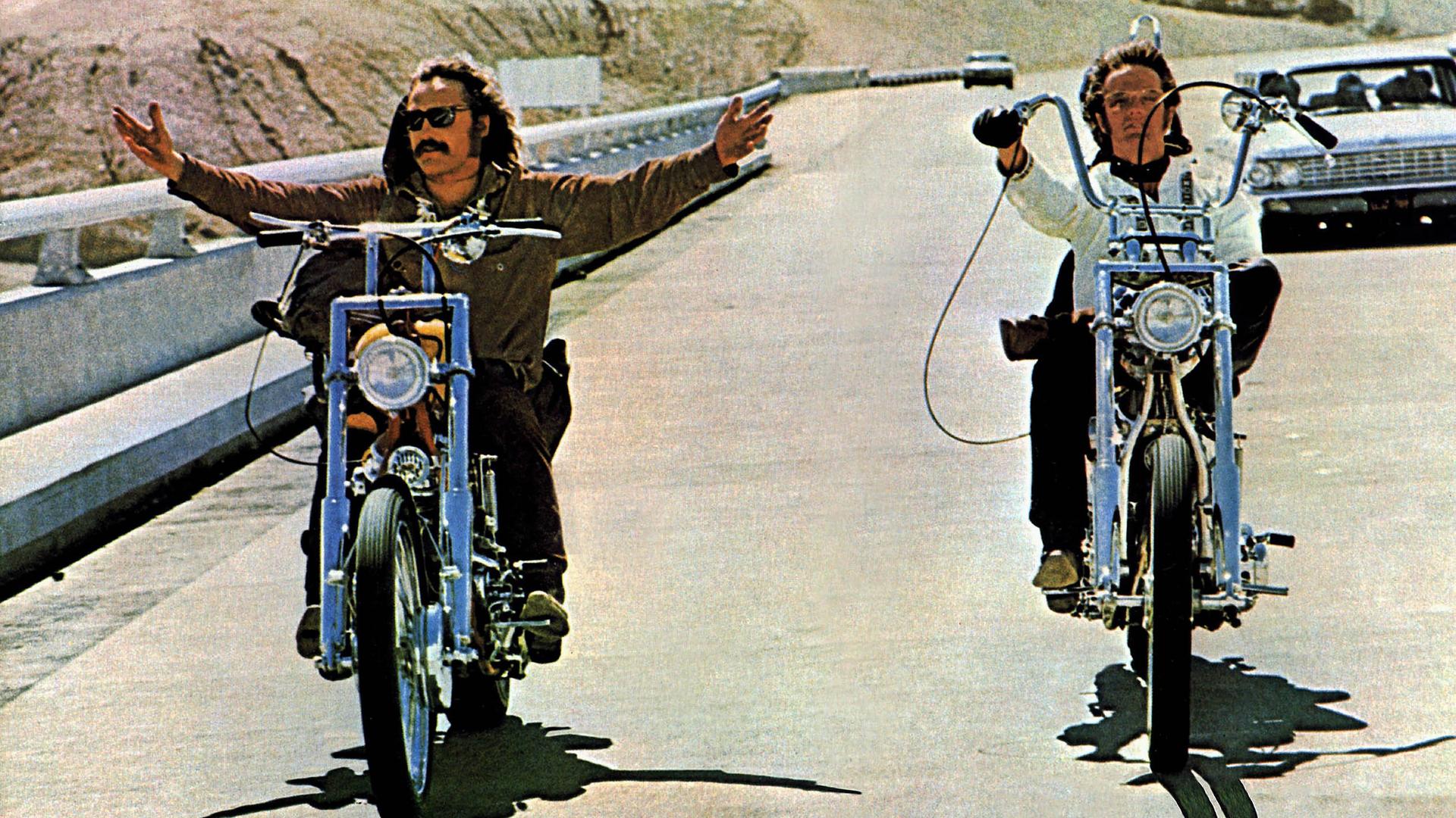 Dennis Hopper und Peter Fonda fahren in einer Filmszene mit Chopper-Motorrädern nebeneinander. Dennis Hopper (l.) fährt freihändig und breitet die Arme aus. Dennis Hopper und Peter Fonda fahren in einer Filmszene mit Chopper-Motorrädern nebeneinander. Dennis Hopper (l.) fährt freihändig und breitet die Arme aus.