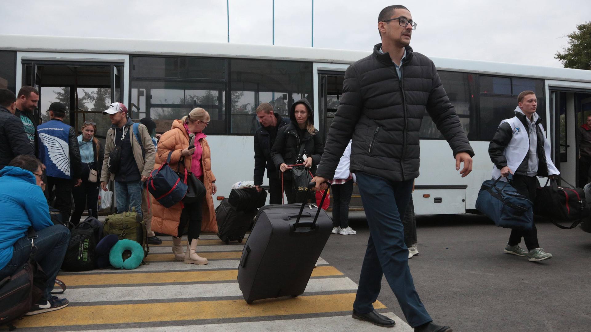 Menschen, die Cherson auf russische Aufforderung hin verlassen haben, verlassen einen Bus in der Nähe eines Bahnhofs auf der Krim
