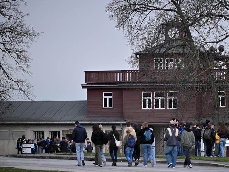 Das Lagertor der Gedenkstätte Buchenwald. Davor stehen Besucher des früheren Konzentrationslagers. 