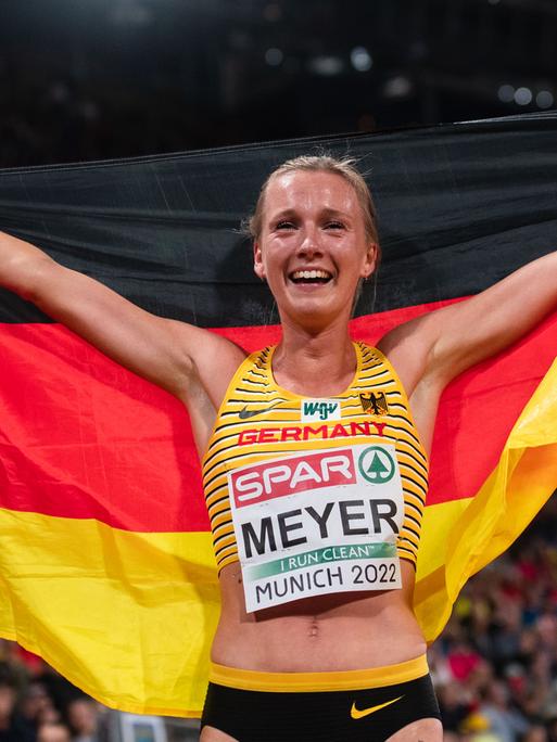 Lea Meyer jubelt im Ziel und hält die Deutschland-Flagge.