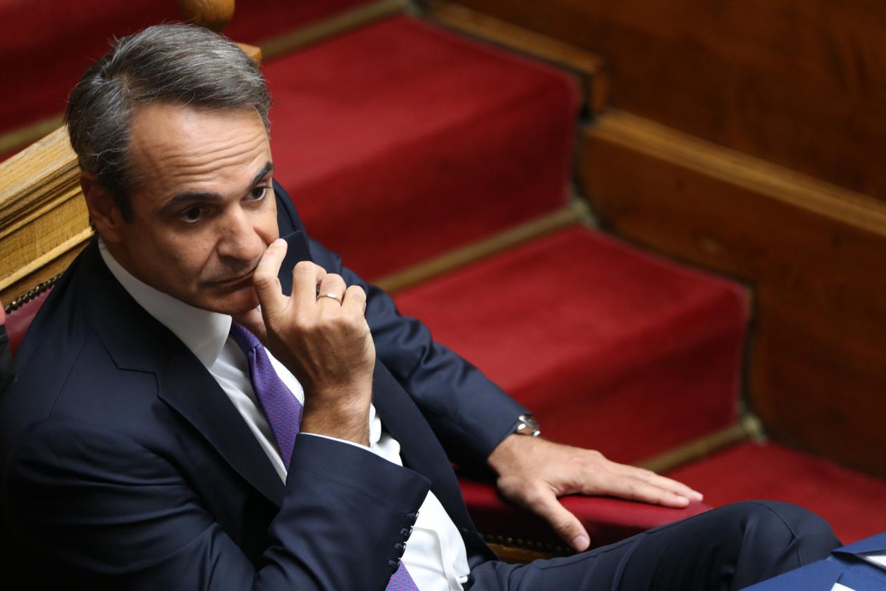 Kyriakos Mitsotakis sitzt mit nachdenklichem Gesichtsausdruck, den Kopf in die Hand gestützt, im Parlament.