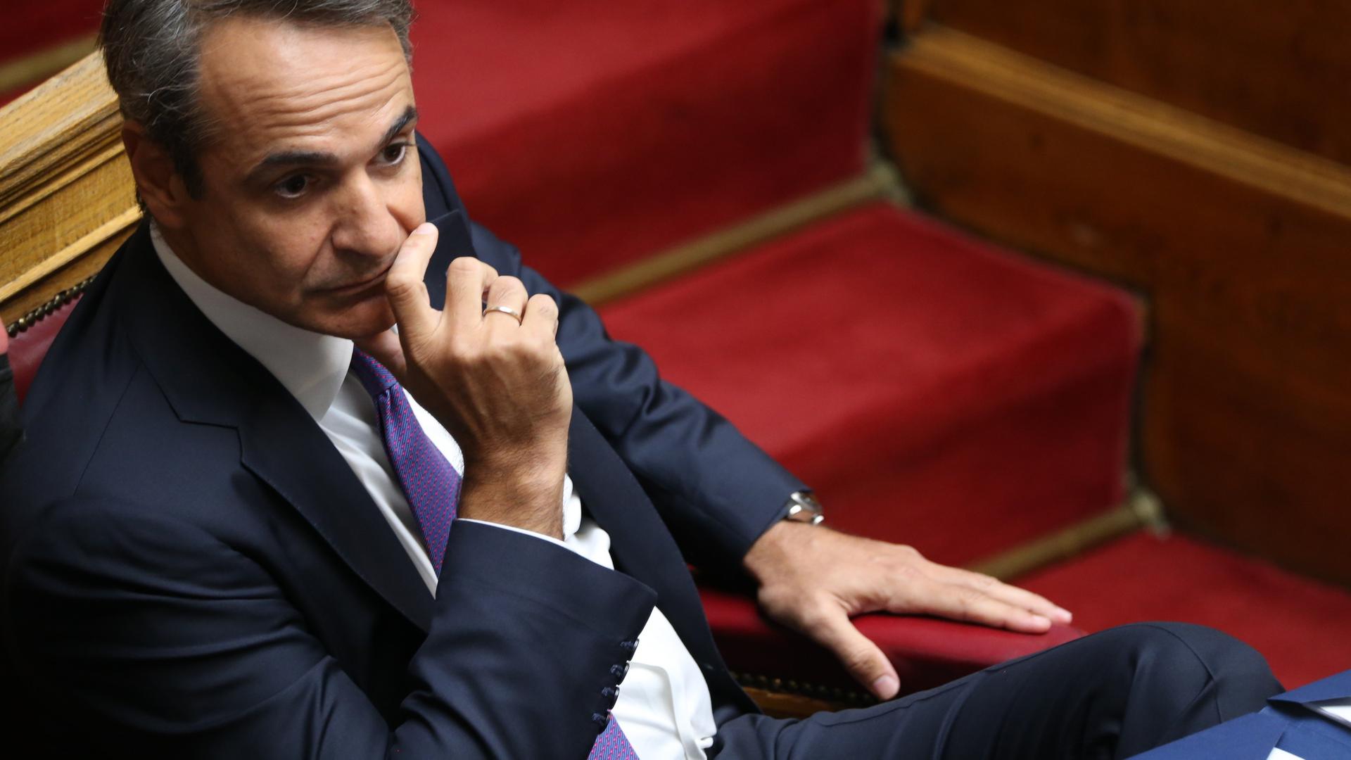 Kyriakos Mitsotakis sitzt mit nachdenklichem Gesichtsausdruck, den Kopf in die Hand gestützt, im Parlament. Kyriakos Mitsotakis sitzt mit nachdenklichem Gesichtsausdruck, den Kopf in die Hand gestützt, im Parlament.