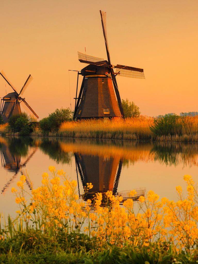 Die zum UNESCO-Welterbe zählenden Windmühlen von Kinderdijk bei Sonnenaufgang über den Kanal hinweg aufgenommen. Die zum UNESCO-Welterbe zählenden Windmühlen von Kinderdijk bei Sonnenaufgang über den Kanal hinweg aufgenommen.