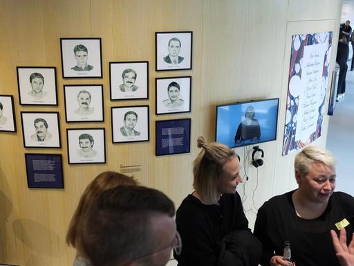 Das Bild zeigt Fotos von den Opfern der NSU-Anschläge an einer Wand. Davor stehen Besucher des NSU-Dokumentationszentrum in Chemnitz 
