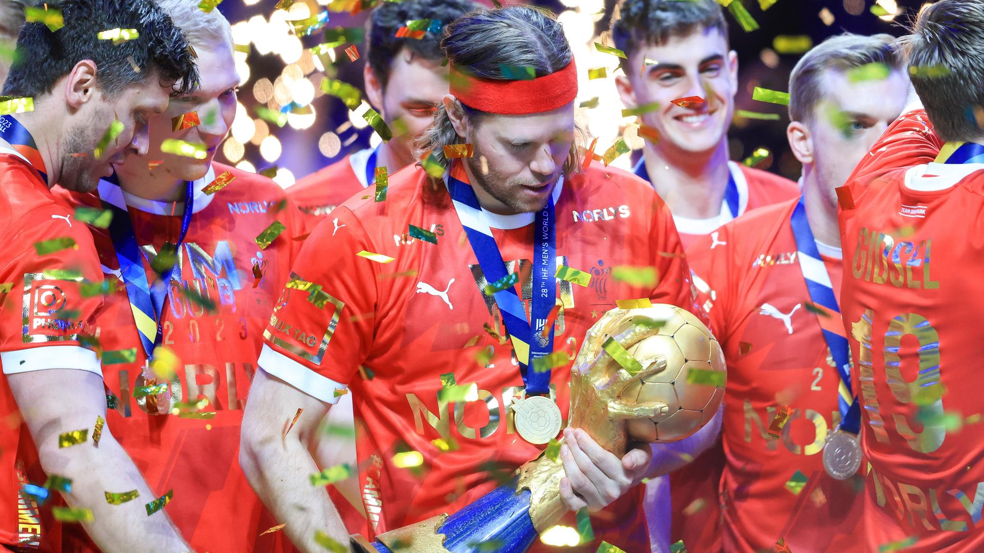 Dänemarks Handball-Spieler Mikkel Hansen betrachtet im Konfetti-Regen den Weltmeister-Pokal.