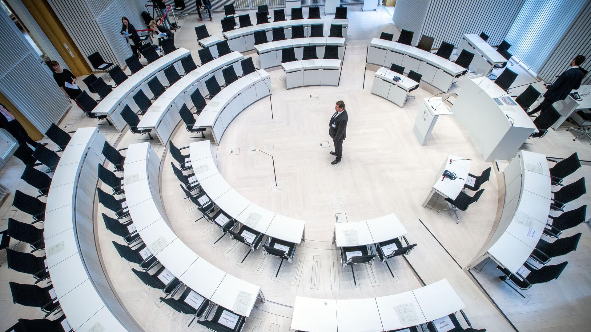 Ein Landtagsmitarbeiter prüft die Sitzordnung mit größeren Abständen zwischen den Abgeordnetenplätzen vor dem Beginn einer Landtagssitzung im Jahr 2020 mit dezimierter Beteiligung