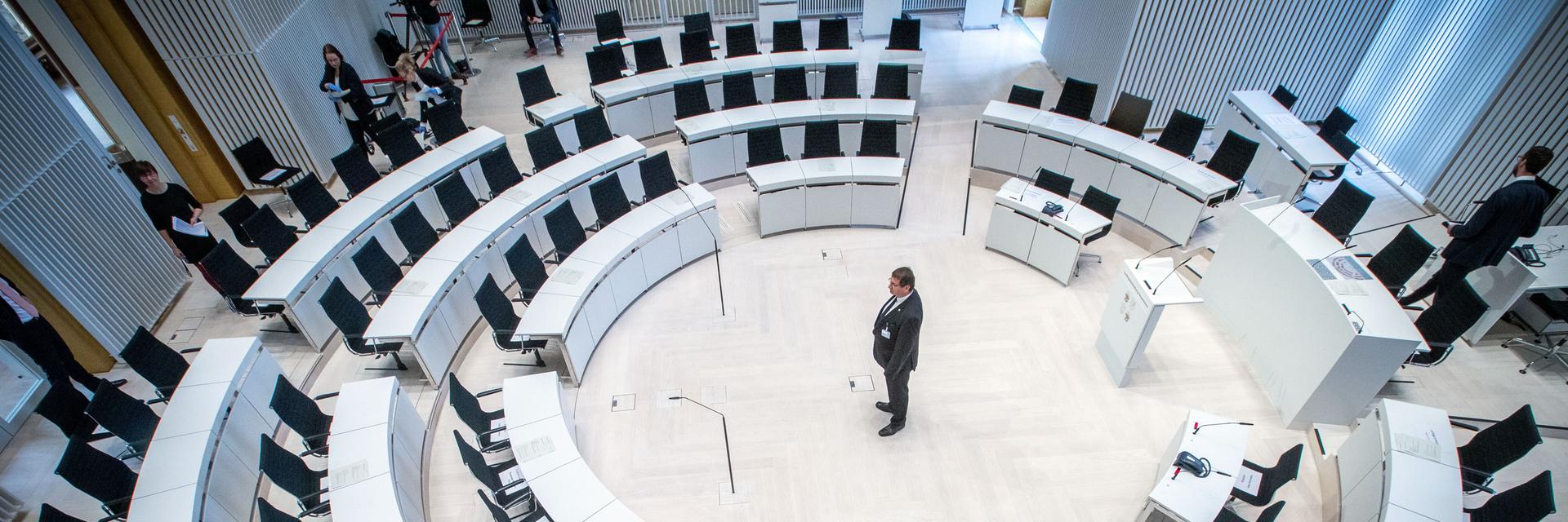 Ein Landtagsmitarbeiter prüft die Sitzordnung mit größeren Abständen zwischen den Abgeordnetenplätzen vor dem Beginn einer Landtagssitzung im Jahr 2020 mit dezimierter Beteiligung
