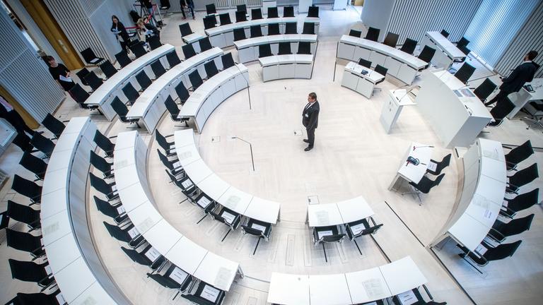 Ein Landtagsmitarbeiter prüft die Sitzordnung mit größeren Abständen zwischen den Abgeordnetenplätzen vor dem Beginn einer Landtagssitzung im Jahr 2020 mit dezimierter Beteiligung