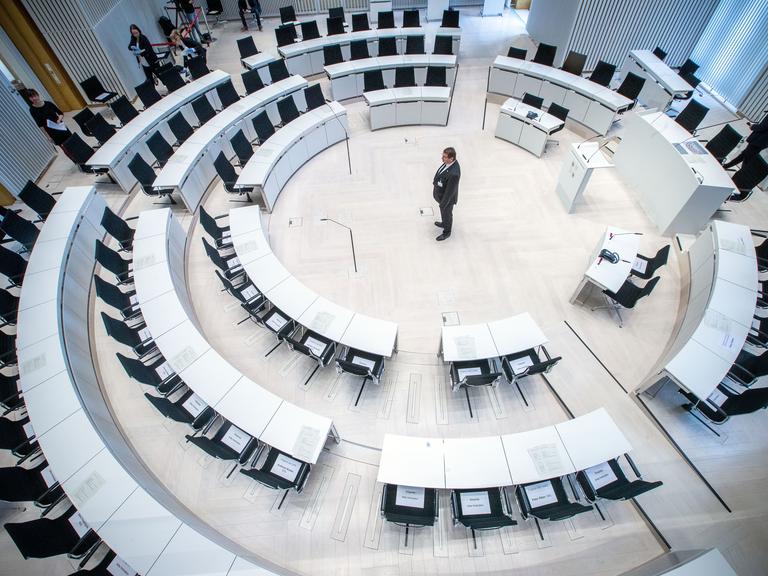Ein Landtagsmitarbeiter prüft die Sitzordnung mit größeren Abständen zwischen den Abgeordnetenplätzen vor dem Beginn einer Landtagssitzung im Jahr 2020 mit dezimierter Beteiligung