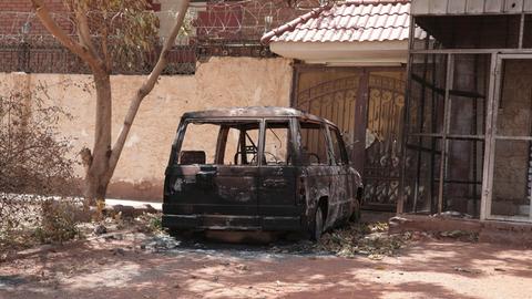 Sudan, Khartum: Ein zerstörtes Militärfahrzeug steht während anhaltender Kämpfe in der Stadt vor einem Haus.