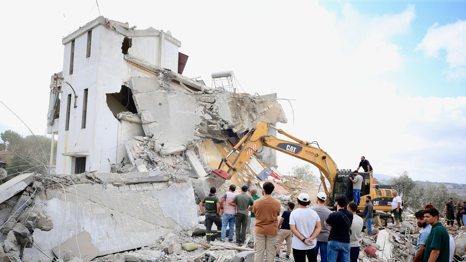 Menschen stehen vor einem bei einem israelischen Luftangriff zerstörten Haus im Südlibanon. Menschen stehen vor einem bei einem israelischen Luftangriff zerstörten Haus im Südlibanon.