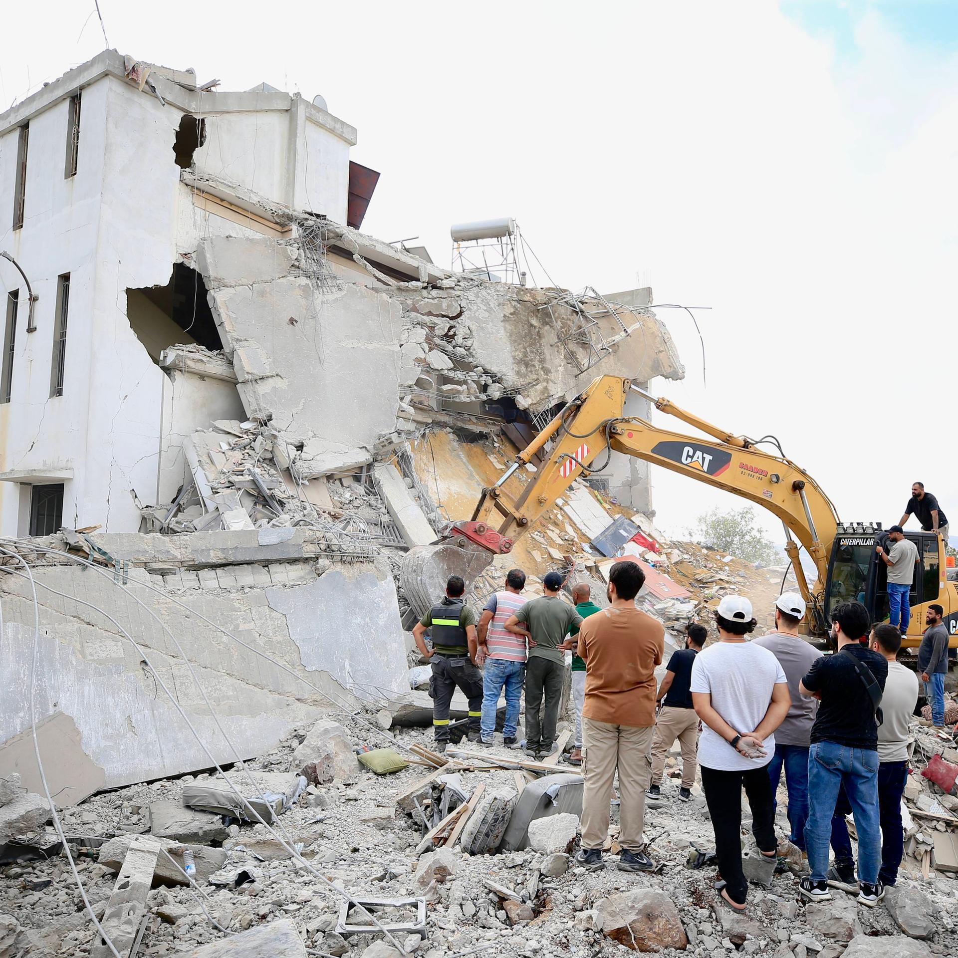 Menschen stehen vor einem bei einem israelischen Luftangriff zerstörten Haus im Südlibanon.