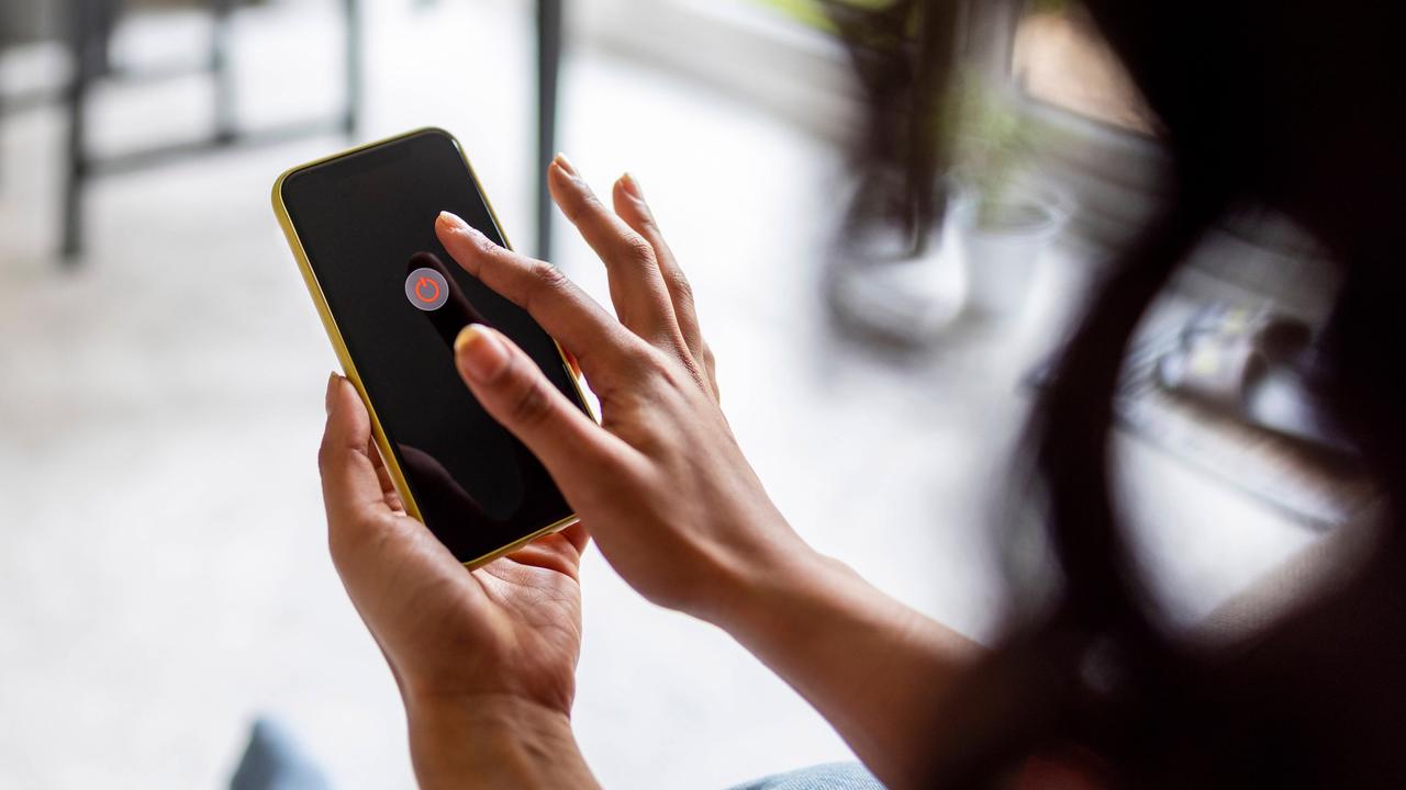 Eine Frau hält ein Handy in der Hand. Auf dem Handybildschirm ist ein Ausschalte-Knopf zu sehen. 