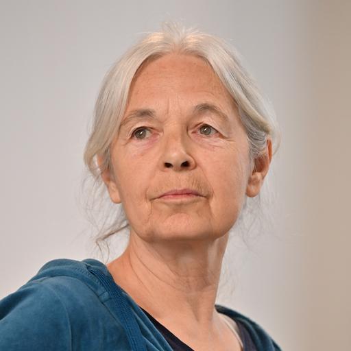 Ein Bild von Klettes grauhaarigem Kopf vor grauem Hintergrund. Sie schaut neutral.