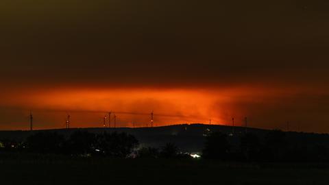Nachtaufnahme: Am Horizont erhellt rötlicher Flammenschein den Brandrauch des Großbrands im Hohen Venn.