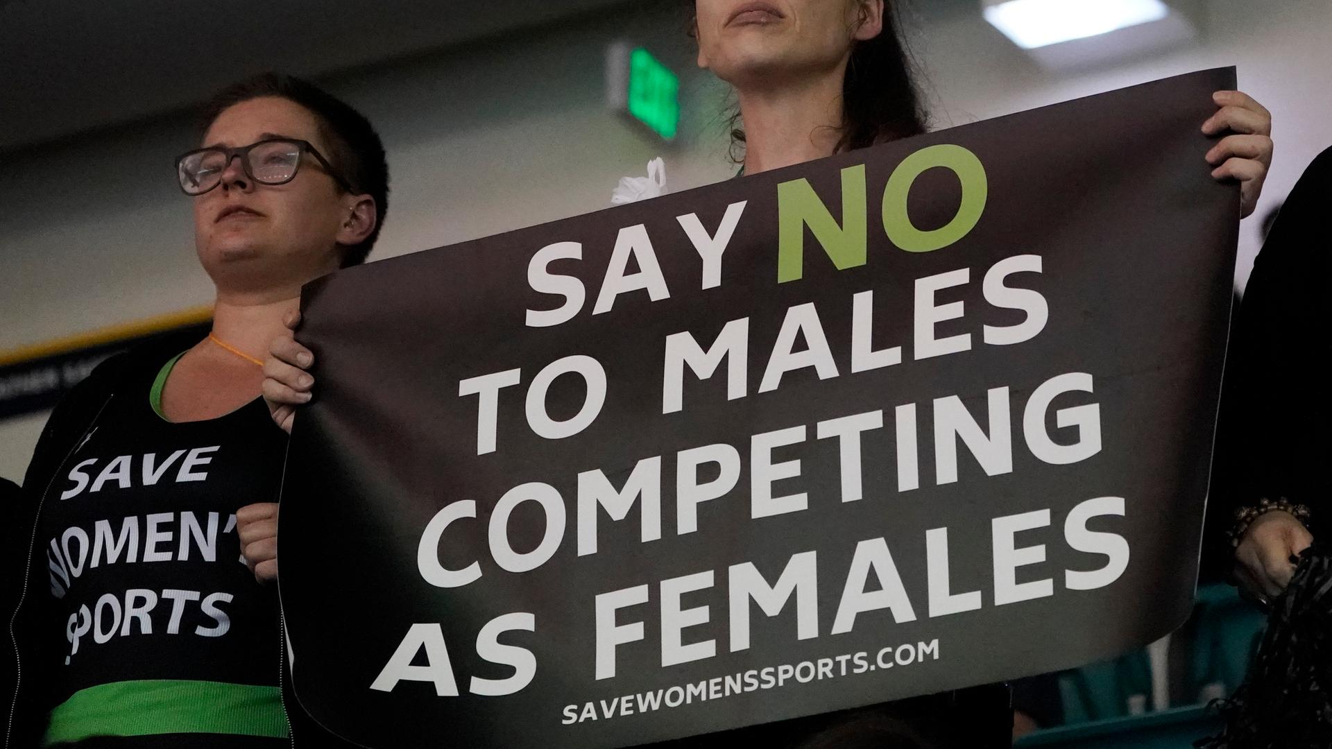 Beim Finale der US-College-Meisterschaften 2022 in Atlanta, wo Lia Thomas als erste Transgender-Schwimmerin einen Titel holte, kam es im Publikum zu Protesten. Eine Frau hält ein Banner hoch, wo der Ausschluss von transgender Sportlerinnen in Frauen-Wettbewerben gefordert wird. 
