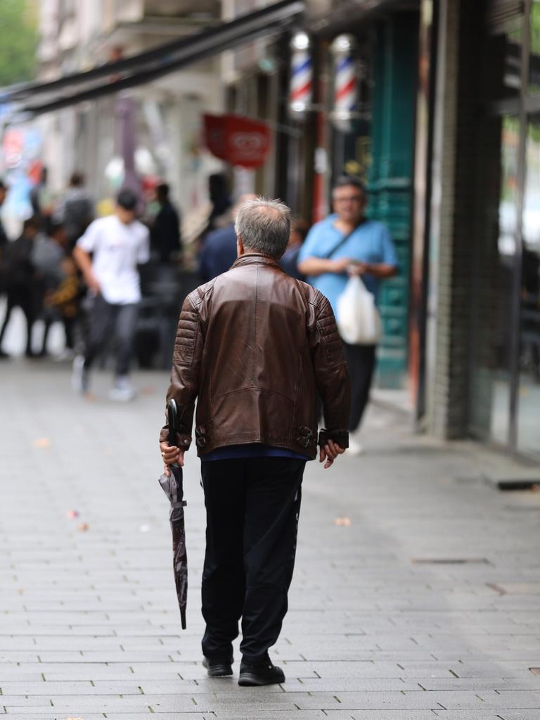 Einige Menschen gehen und stehen bei regnerischem Wetter in einer Fußgängerzone. Einige Menschen gehen und stehen bei regnerischem Wetter in einer Fußgängerzone.