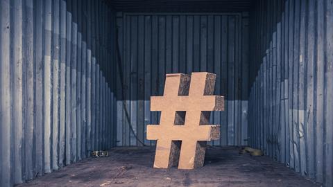 Ein Hashtag-Zeichen aus Pappkarton steht in einem Raum.