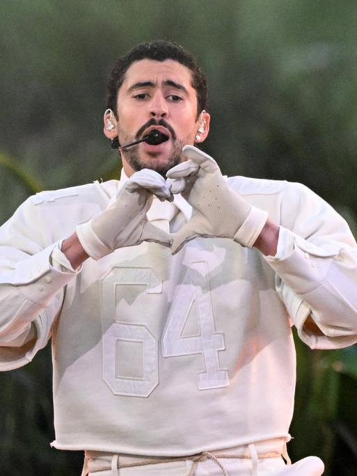 Der Musiker Bad Bunny formt singend auf der Bühne mit seinen Händen ein Herz.