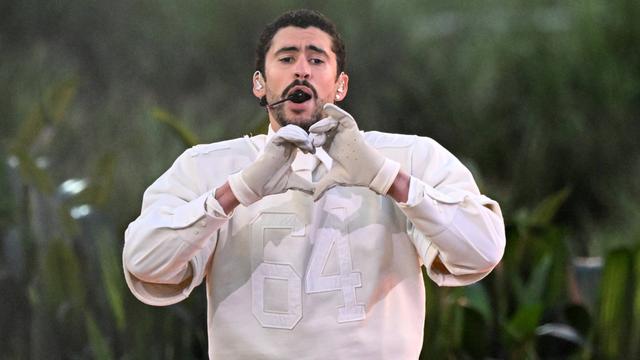 Der Musiker Bad Bunny formt singend auf der Bühne mit seinen Händen ein Herz.