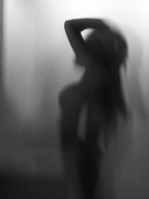 Die Silhouette einer weiblichen Person hinter eine Milchglasscheibe.