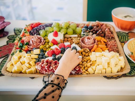 Eine Hand greift nach einem Objekt auf einem Blech übervoll mit Lebensmitteln
