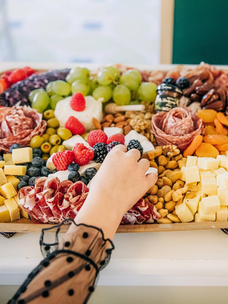 Eine Hand greift nach einem Objekt auf einem Blech übervoll mit Lebensmitteln