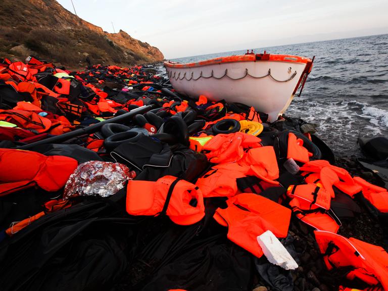 Ein Boot und ein Berg Rettungswesten liegen an der Küste von Lesbos. (2015)