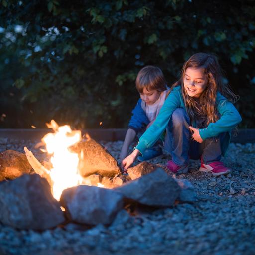 Zwei Kinder hocken an einem kleinen Feuer.