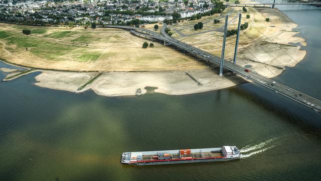 Ein Containerschiff fährt mit geringer Ladung bei Niedrigwasser am Rheinknie in Düsseldorf vorbei.