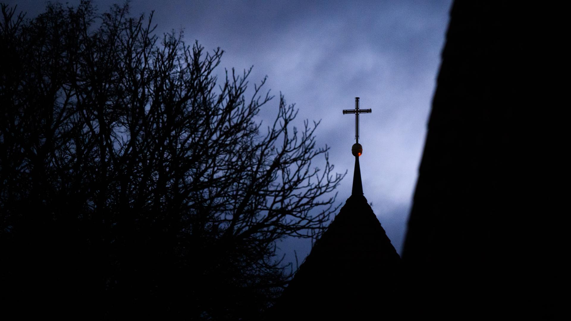 Wolken im Abendhimmel über dem Kreuz auf einem evangelischen Kirchturm Wolken im Abendhimmel über dem Kreuz auf einem evangelischen Kirchturm