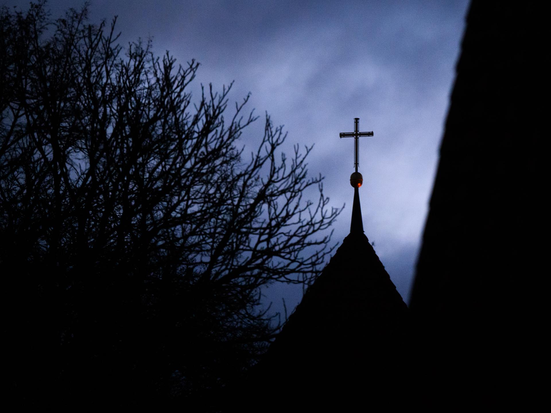 Wolken im Abendhimmel über dem Kreuz auf einem evangelischen Kirchturm