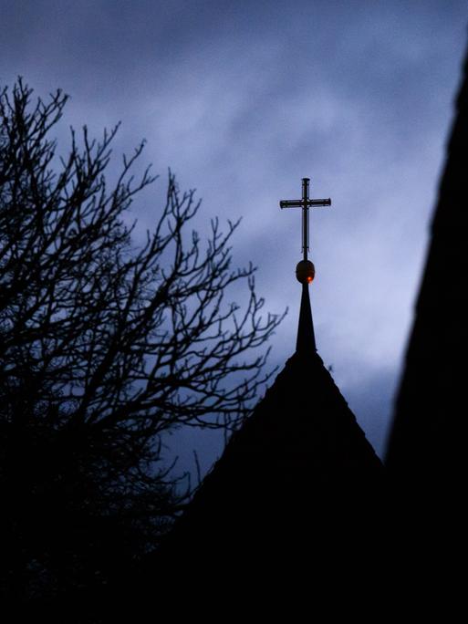 Wolken im Abendhimmel über dem Kreuz auf einem evangelischen Kirchturm Wolken im Abendhimmel über dem Kreuz auf einem evangelischen Kirchturm